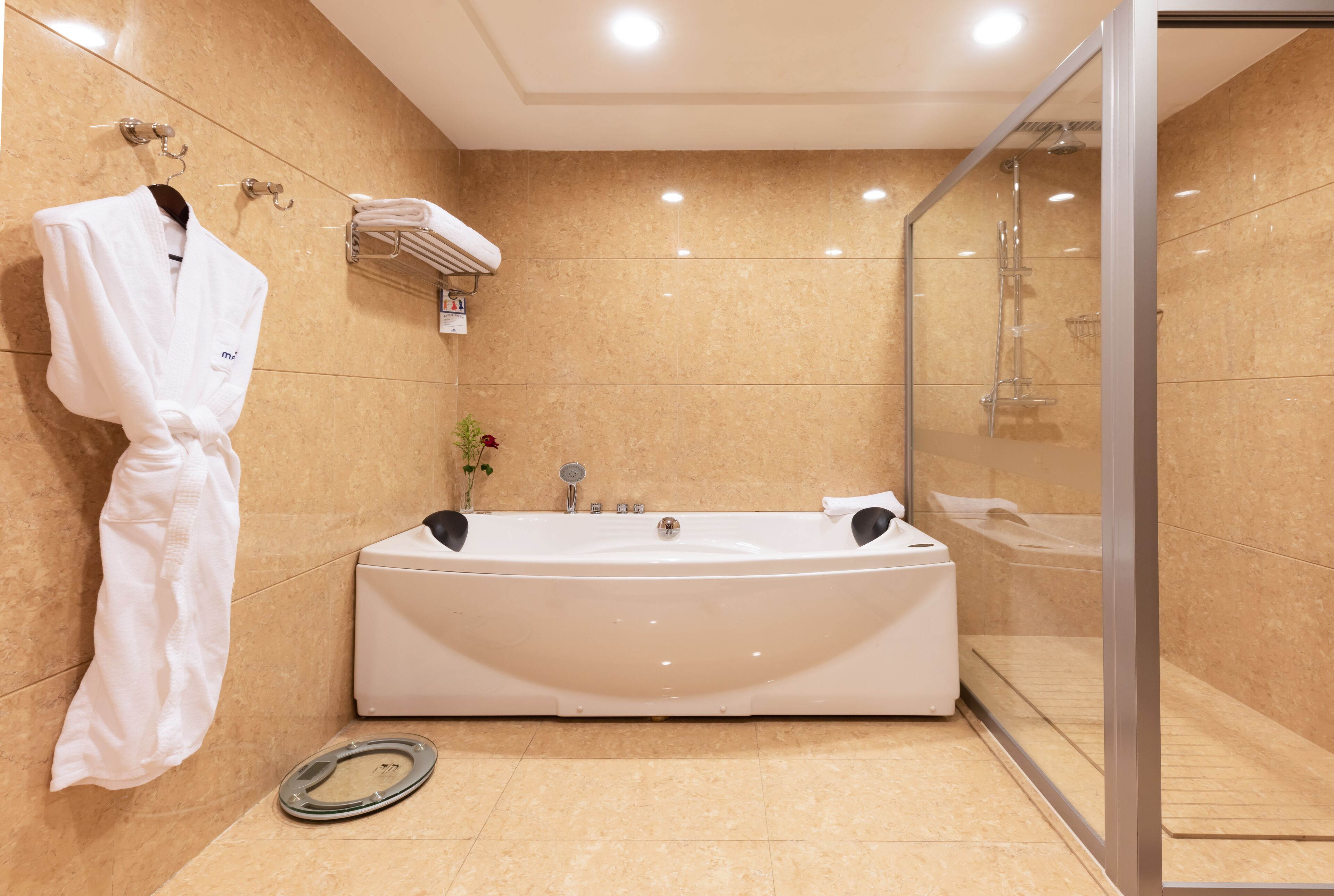 A modern bathroom with a large bathtub, a glass shower enclosure, and a towel rack with a robe.