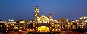 Un hotel grande de varios pisos, con una imponente torre de reloj y una entrada majestuosa.