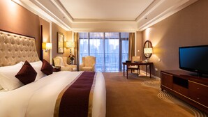 Habitación de hotel con una cama grande, televisión, escritorio y vistas a la ciudad.