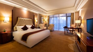A hotel room with a large bed, a desk, a chair, a TV, and a view of the city through large windows. - Country Garden Phoenix Hotels Shenyang Yuhong (Shenyang)