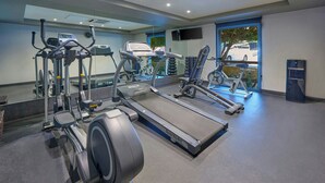 A gym with cardio machines, a mirror, and a view of the outside. - City Express by Marriott San Luis Potosi Zona Universitaria (San Luis Potosi)
