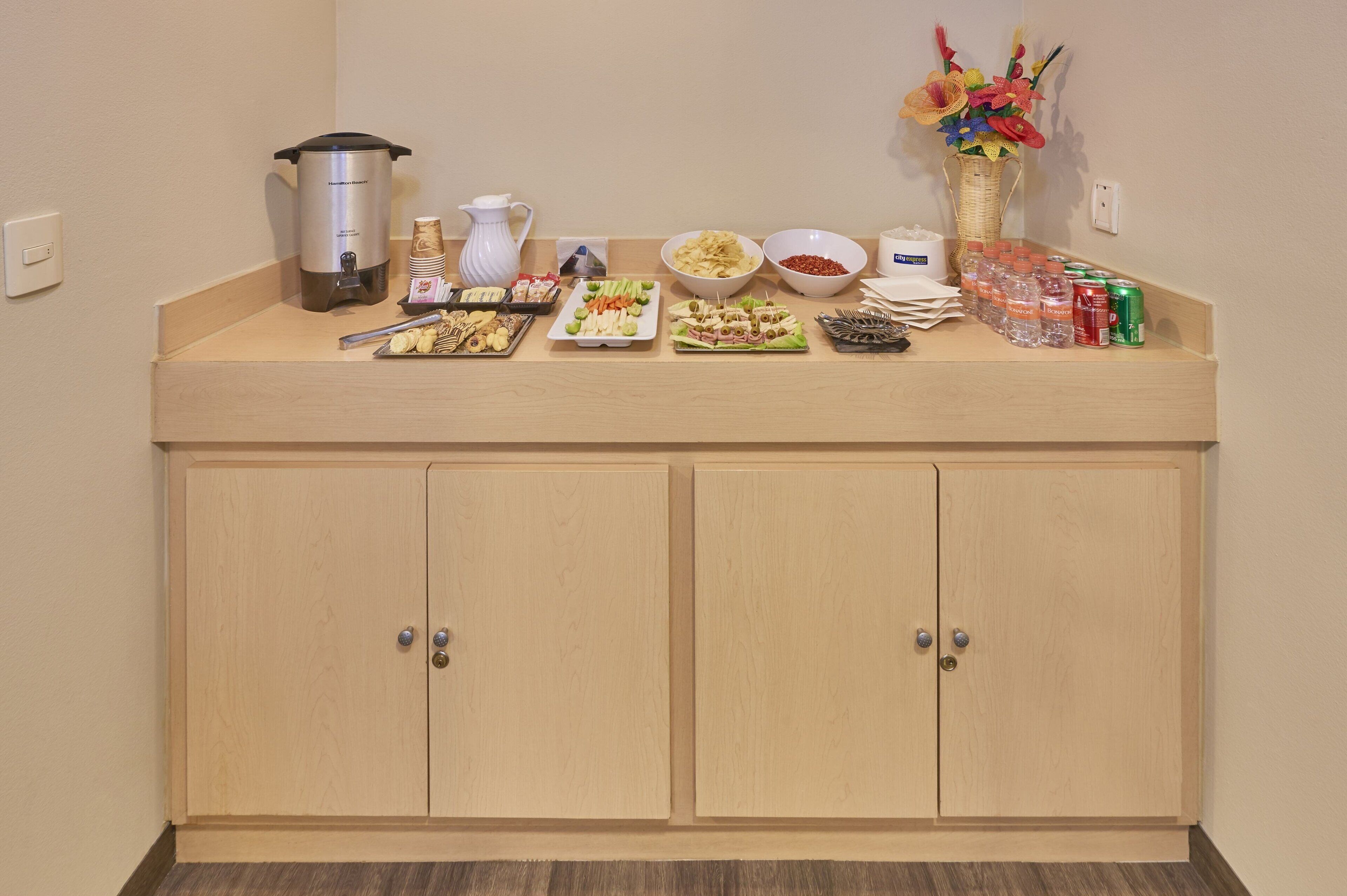 A buffet setup with various food items and beverages on a counter.