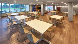 A spacious room with multiple tables and chairs, large windows with a view of the outdoors, and a modern interior design. - City Express by Marriott San Luis Potosi Zona Universitaria (San Luis Potosi)