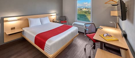 Une chambre d’hôtel avec un grand lit, un bureau, une chaise, une télévision et une fenêtre donnant sur un beau paysage.