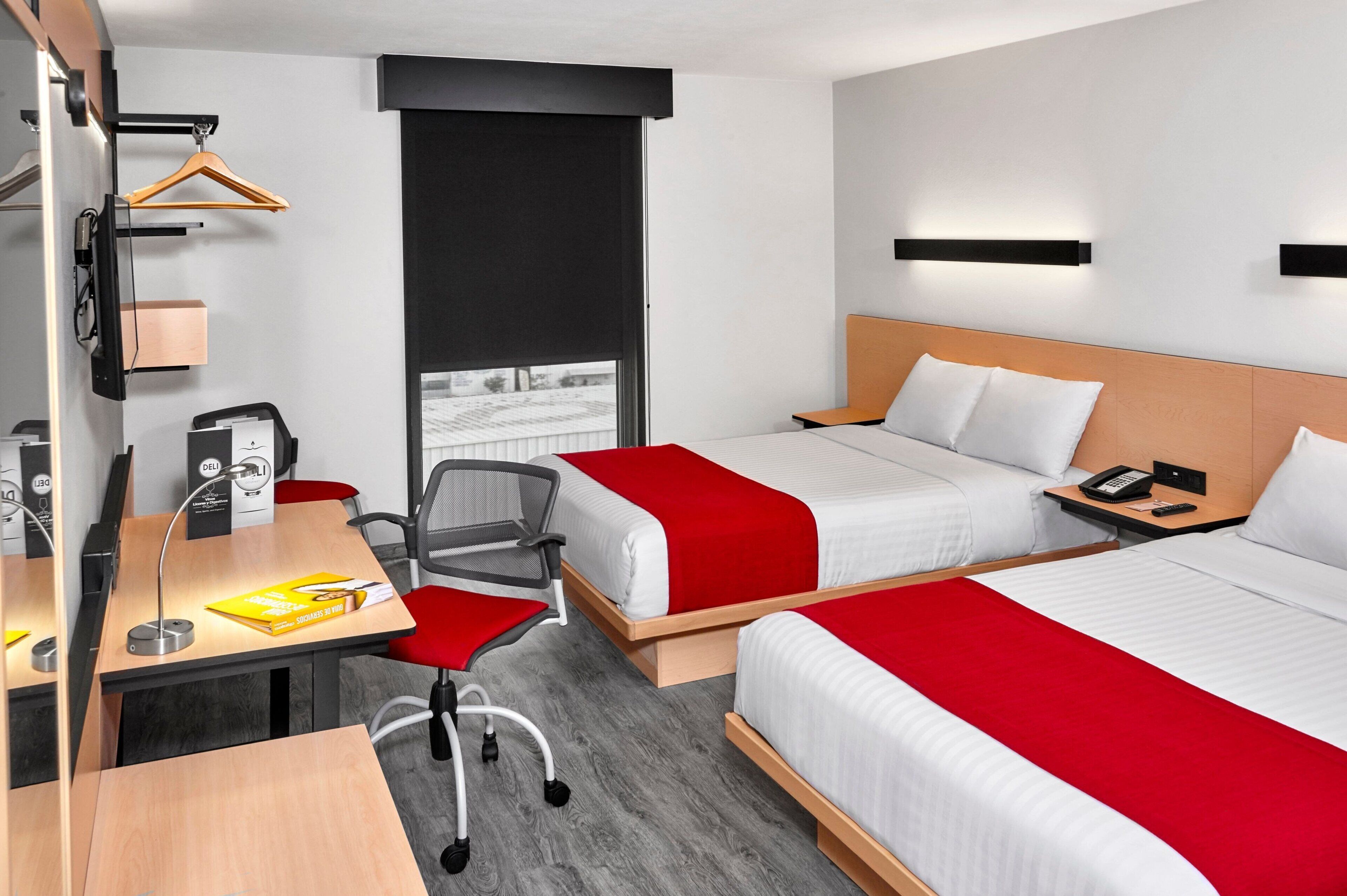 Ein Hotelzimmer mit zwei Betten, einem Schreibtisch mit Stuhl, einem Telefon und einem Fenster mit Blick.