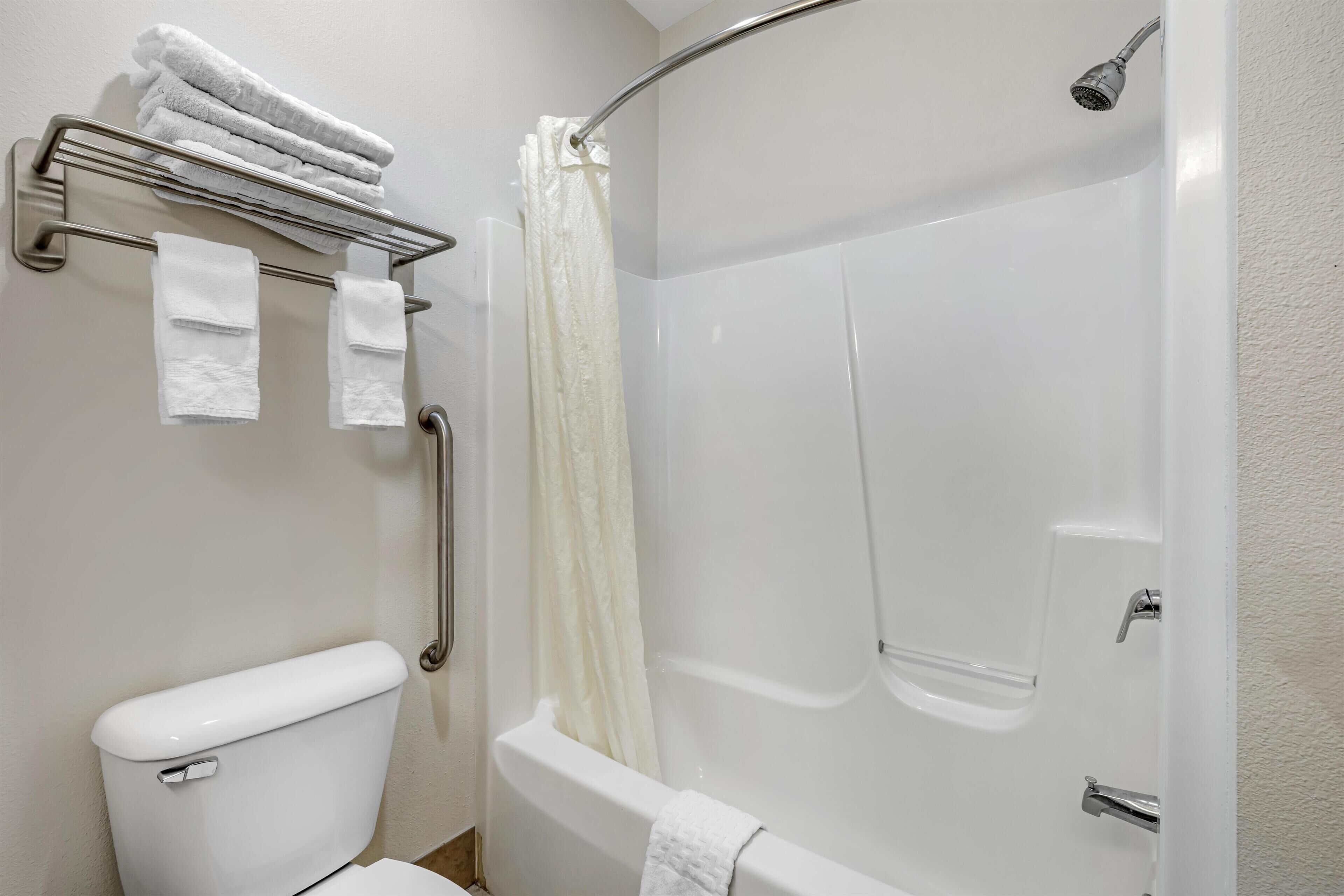 A bathroom with a toilet, a shower with a glass door, and a towel rack with folded towels.