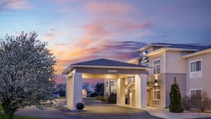 L’entrée d’un hôtel, avec une allée couverte, une enseigne indiquant « meilleur rapport qualité-prix » et un ciel dégagé.