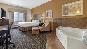 A hotel room with a bed, a desk with a computer, a chair, a bathtub, and a window with curtains. - Best Western Plover-Stevens Point Hotel & Conference Center (Plover)