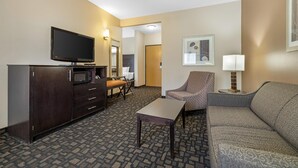 A hotel room with a flat-screen TV, a sofa, a chair, a small table, a microwave, and a cabinet. - Best Western Plover-Stevens Point Hotel & Conference Center (Plover)