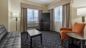A hotel room with a sofa, a small table, a TV, a cabinet, and a chair. - Best Western Plover-Stevens Point Hotel & Conference Center (Plover)