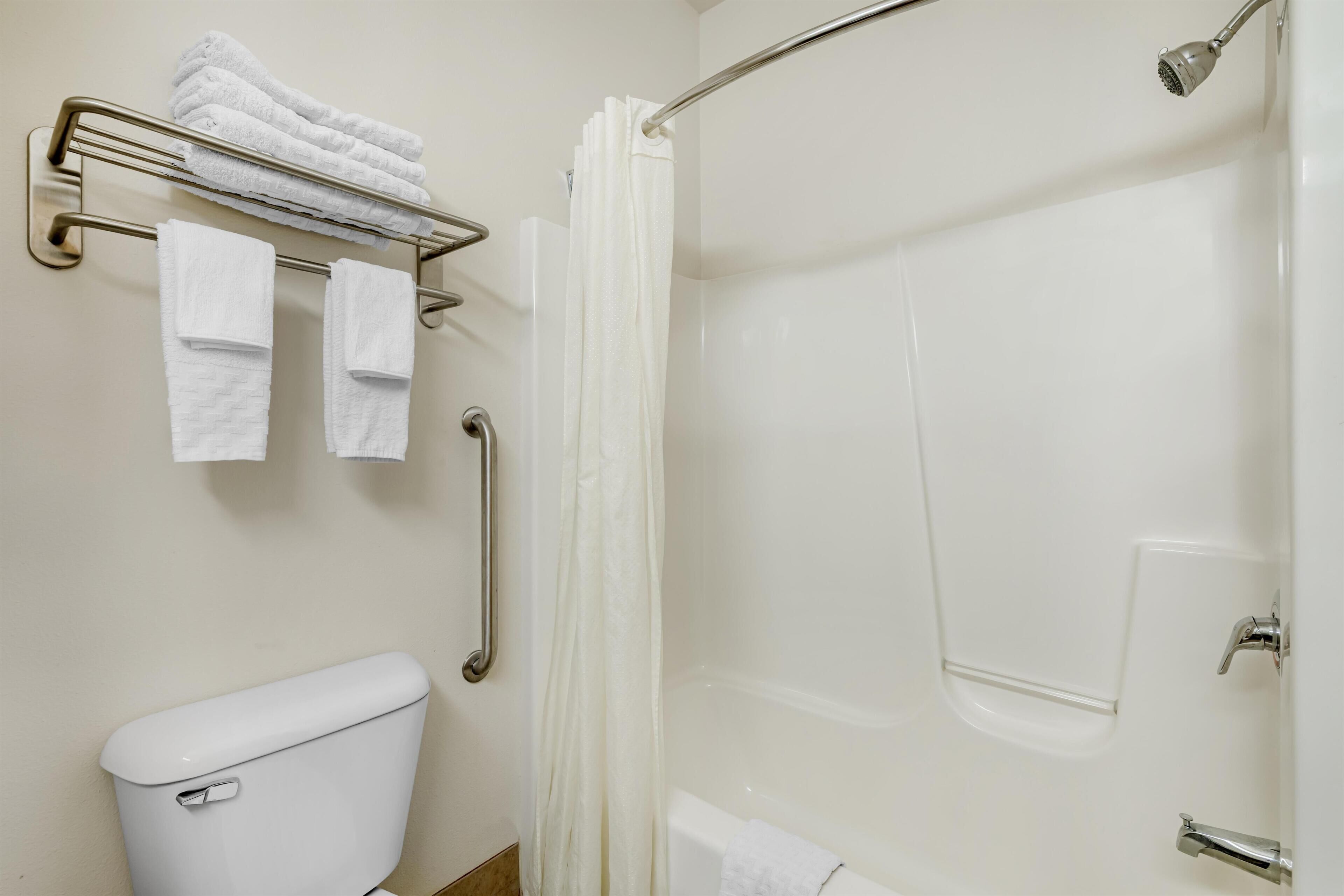 A bathroom with a toilet, a shower with a glass door, and a towel rack with folded towels.