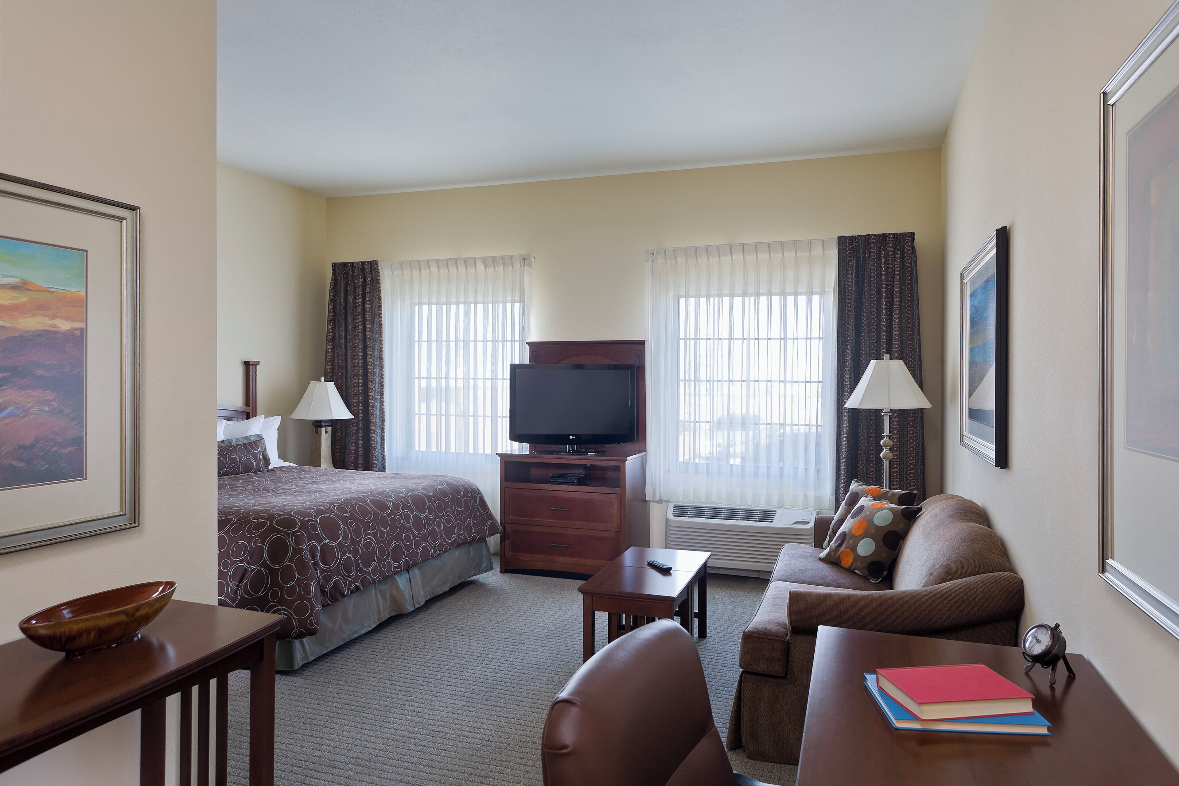 A hotel room with a bed, a TV, a sofa, a desk, and a chair.