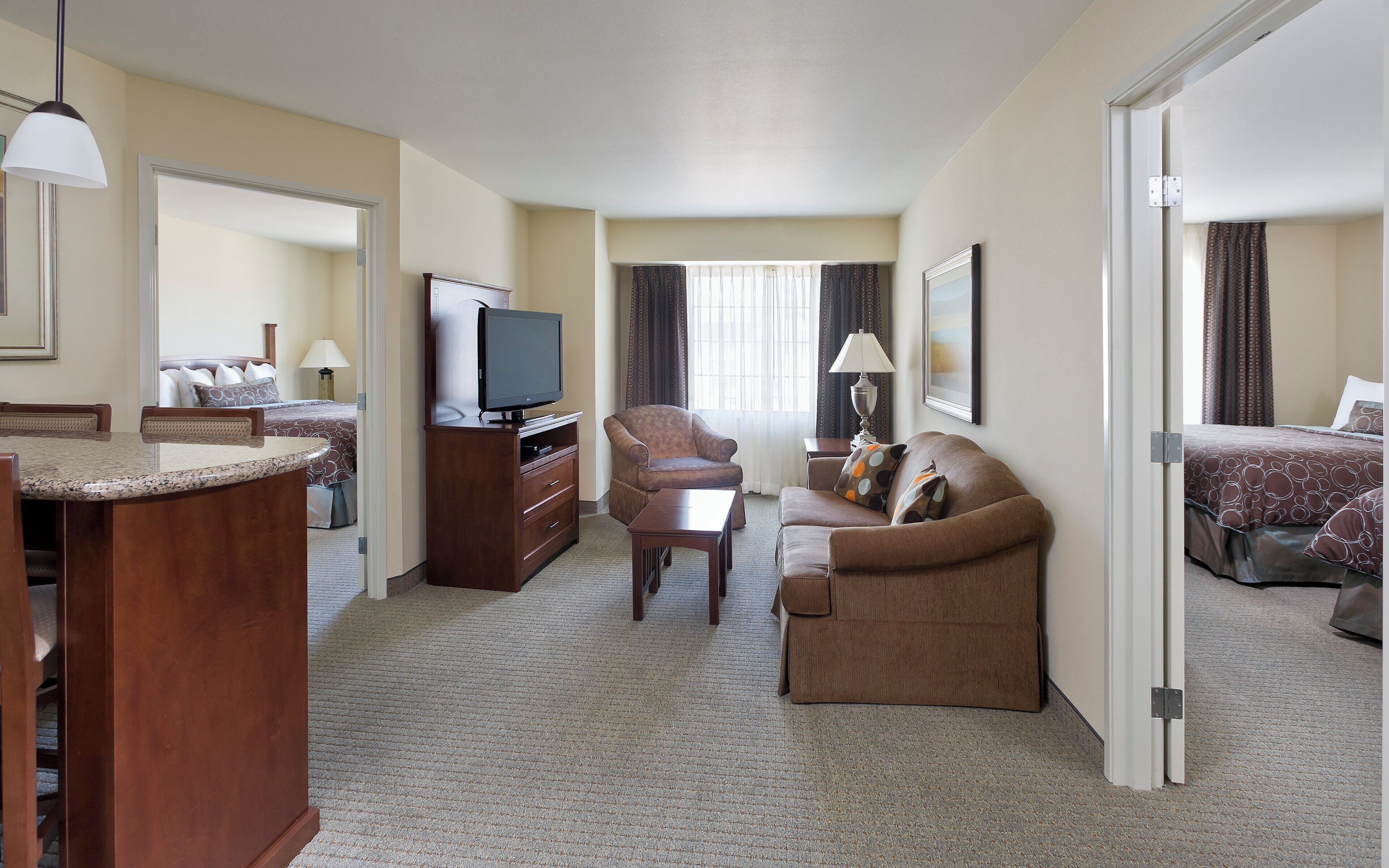 A hotel room with a television, a sofa, a desk, and a bed.