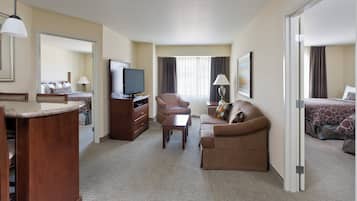 A hotel room with a television, a sofa, a desk, and a bed.
