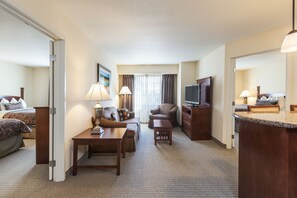 A hotel room with a bed, a sofa, a TV, a desk, and a small table.