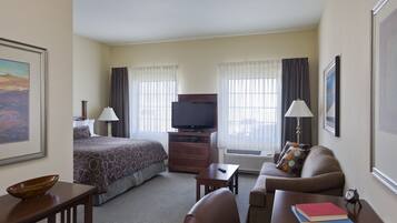 A hotel room with a bed, a television, a desk, a sofa, and a coffee table.
