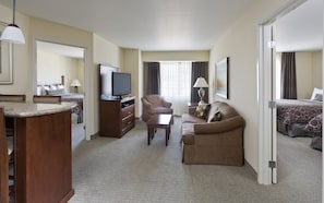 Una habitación de hotel con cama, sofá, televisión, escritorio y silla.