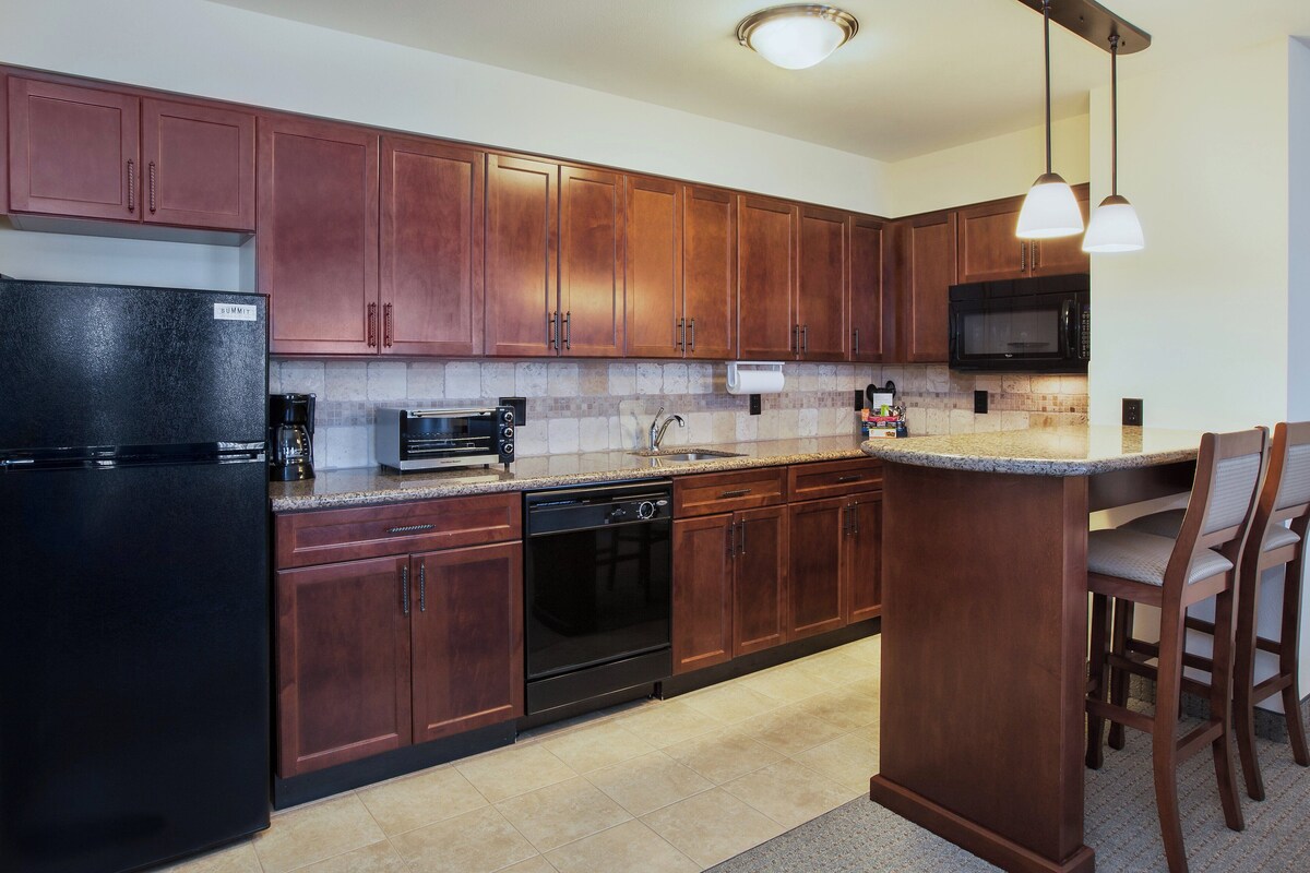 A kitchen with wooden cabinets, a black refrigerator, a microwave, and a dishwasher.