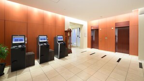 Eine moderne Lobby mit einer Rezeption, Selbstbedienungs-Terminals und einem Aufzug.