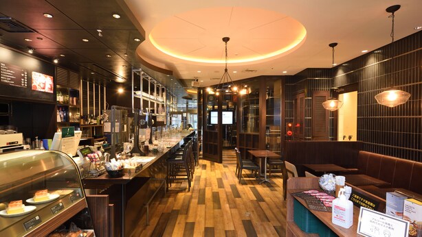 Ein modernes Restaurant mit Holzboden, Bar, Sitzgelegenheiten und einer Vitrine mit Speisen.