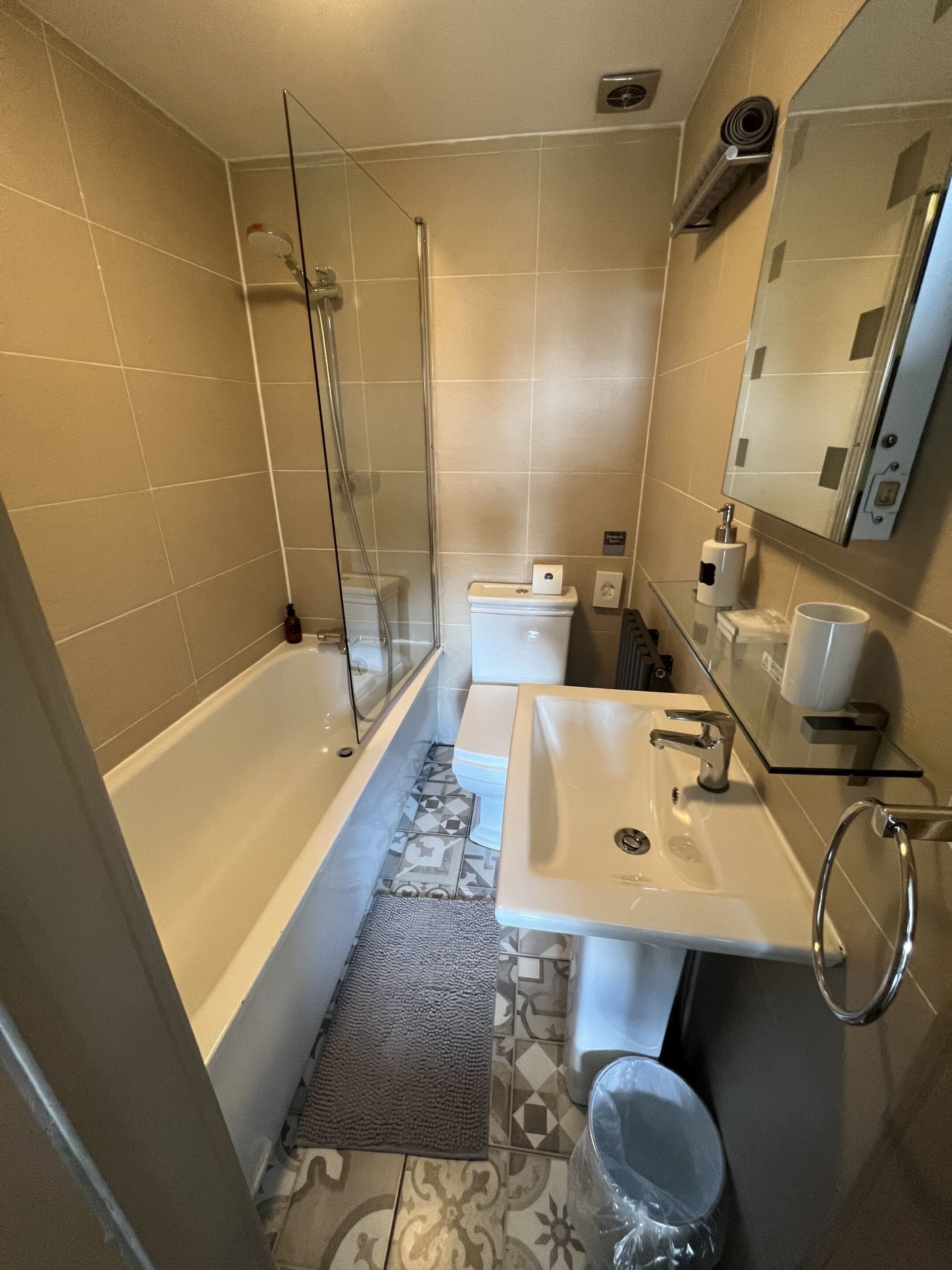 A bathroom with a glass-enclosed shower, a white sink, and a toilet.
