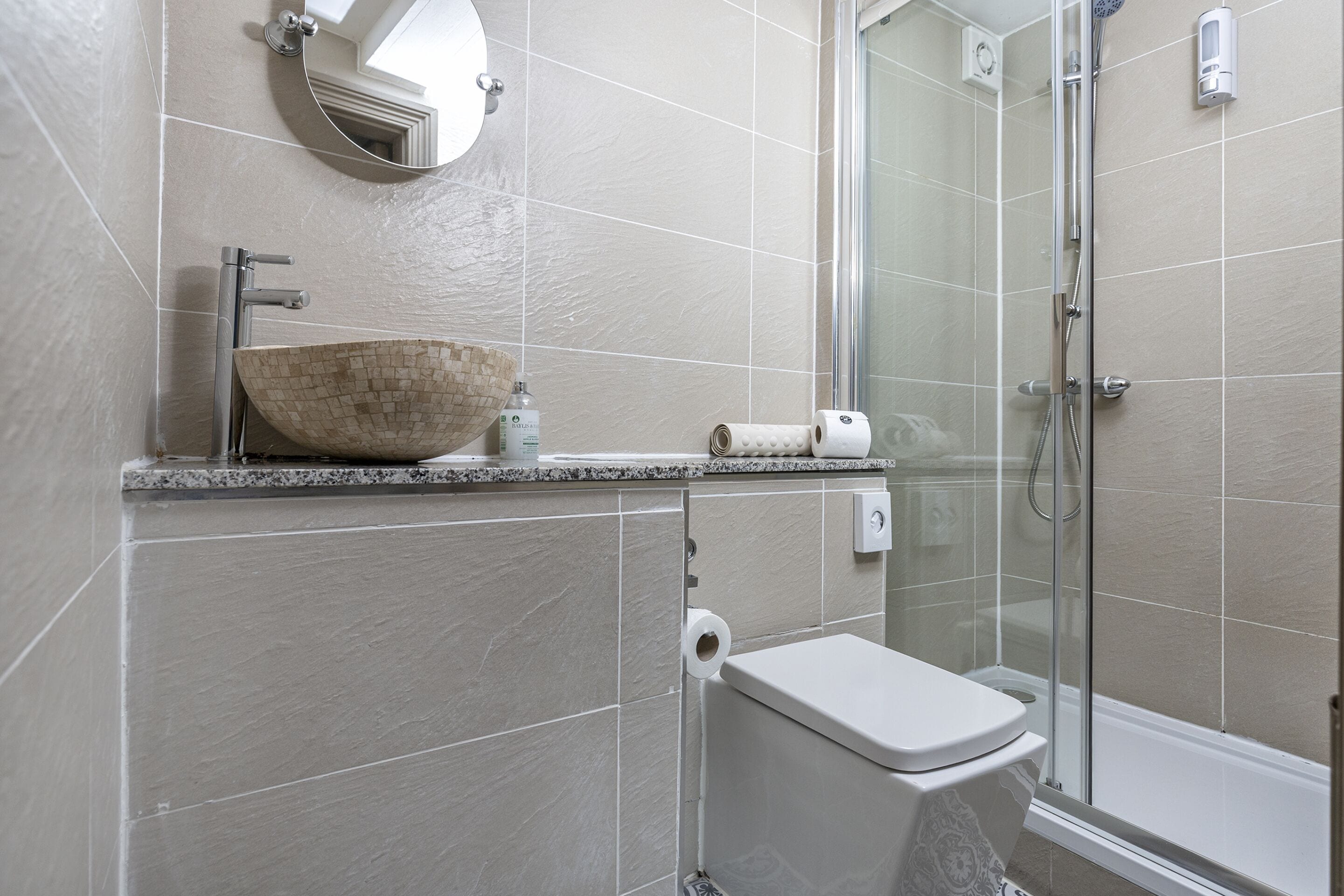 A modern bathroom with a large vessel sink, a toilet, and a glass-enclosed shower area.