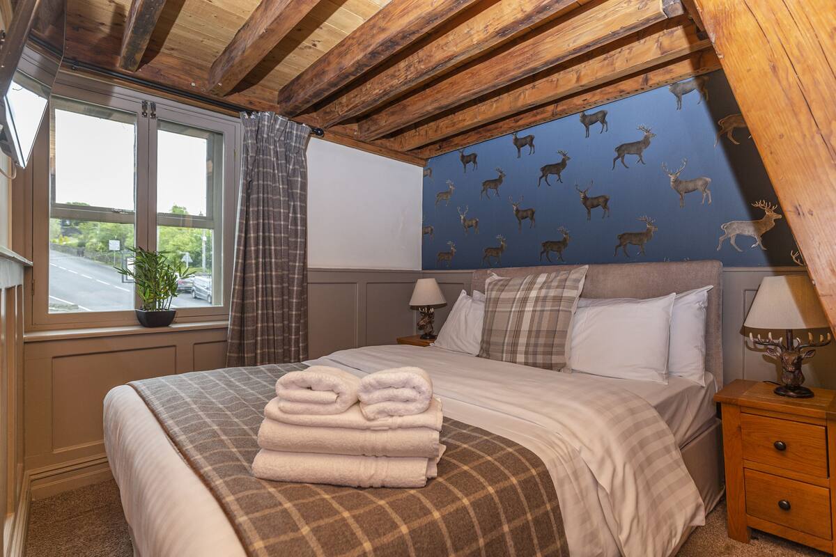 A bedroom with a bed, a nightstand, a lamp, a window with curtains, and a wall with animal decals.