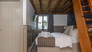A bedroom with a bed, a window with curtains, a wooden ceiling, and a door.