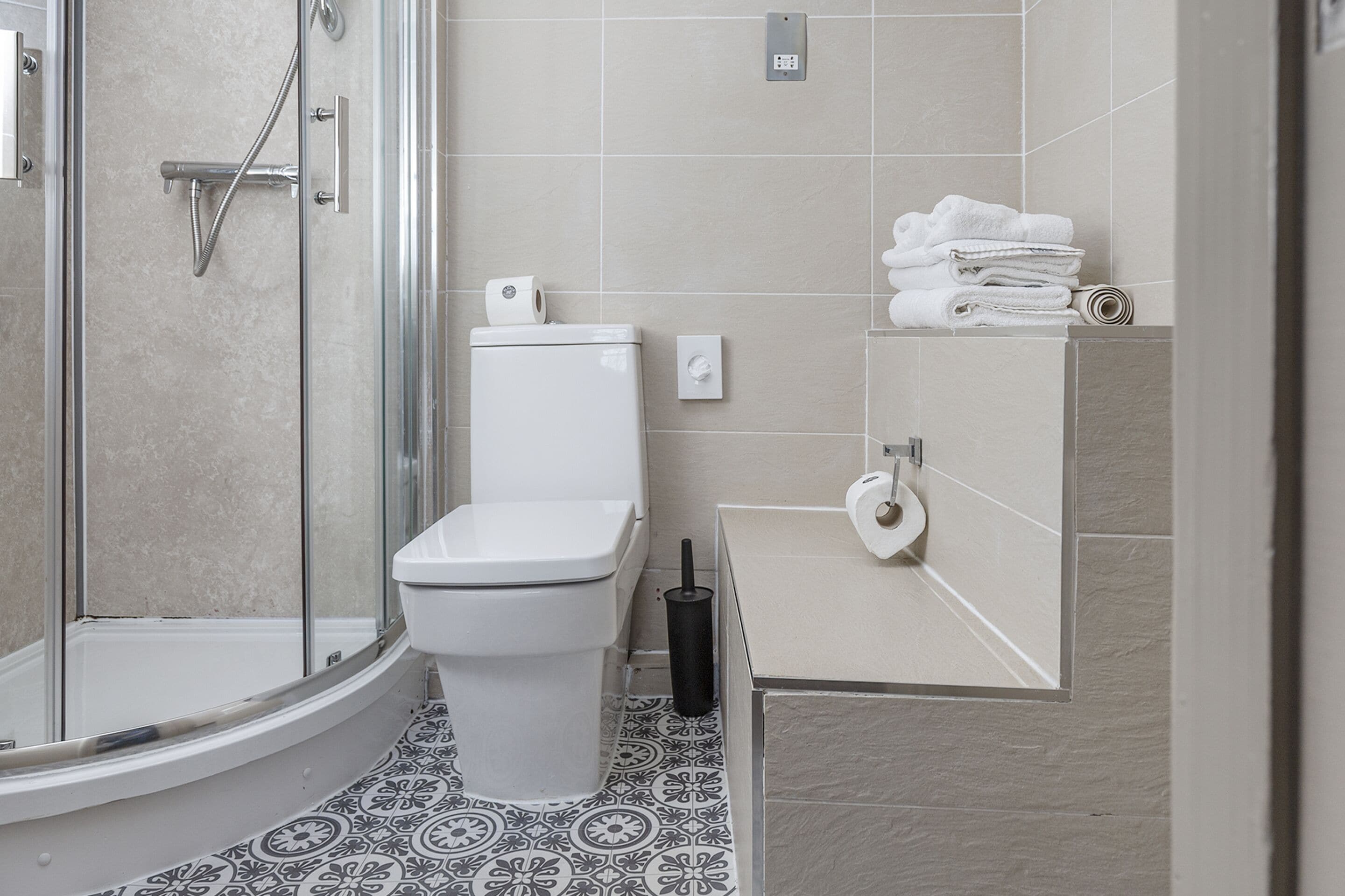 Ein modernes Badezimmer mit einer Duschkabine, einer Toilette und einem Waschplatz mit ordentlich gestapelten Handtüchern.