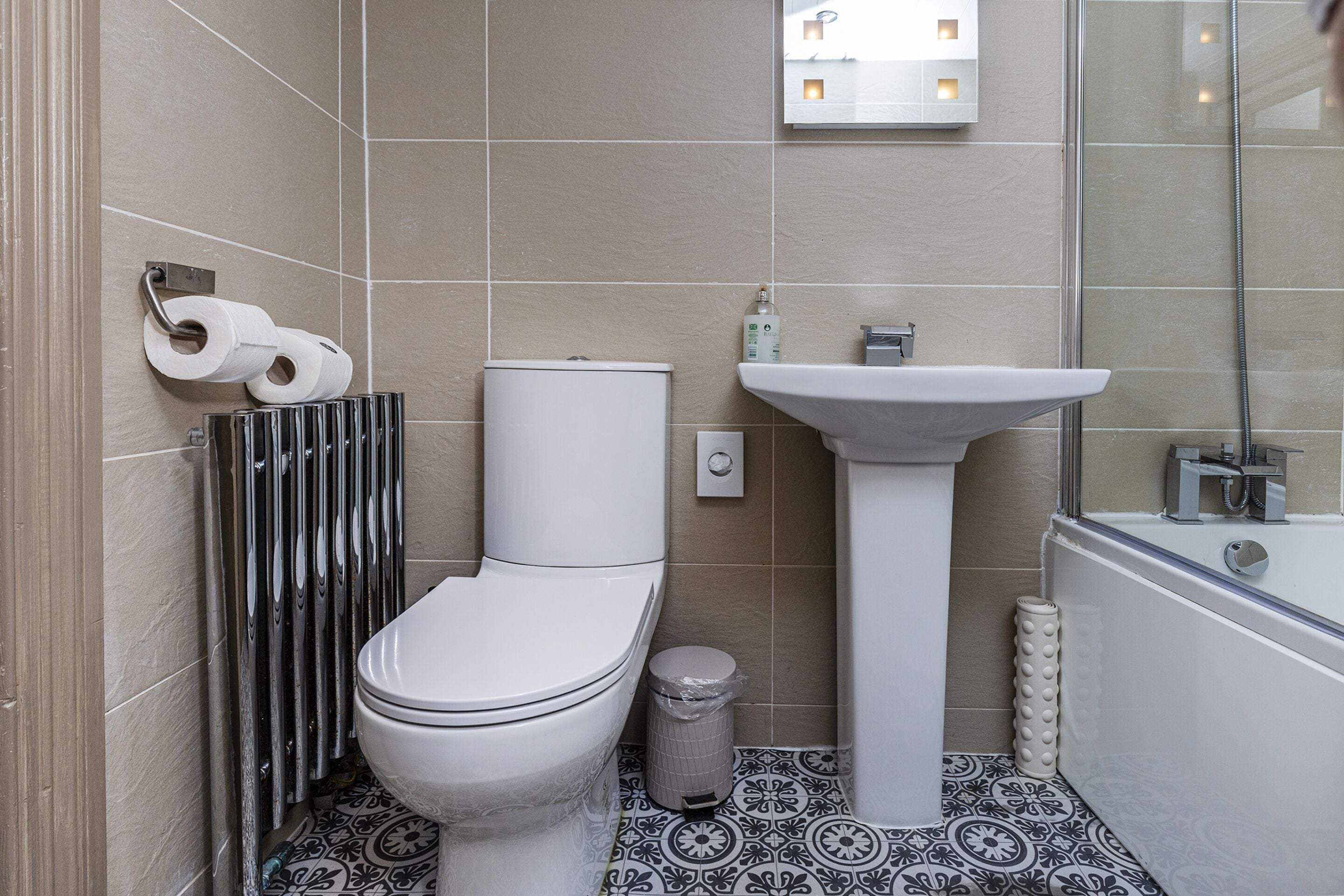 A modern bathroom with a toilet, bidet, sink, and bathtub.