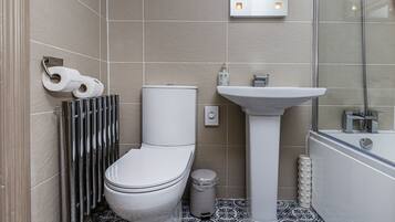 A modern bathroom with a toilet, bidet, sink, and bathtub.
