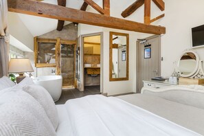 A bedroom with a large bed, a bathtub, and a wooden ceiling.