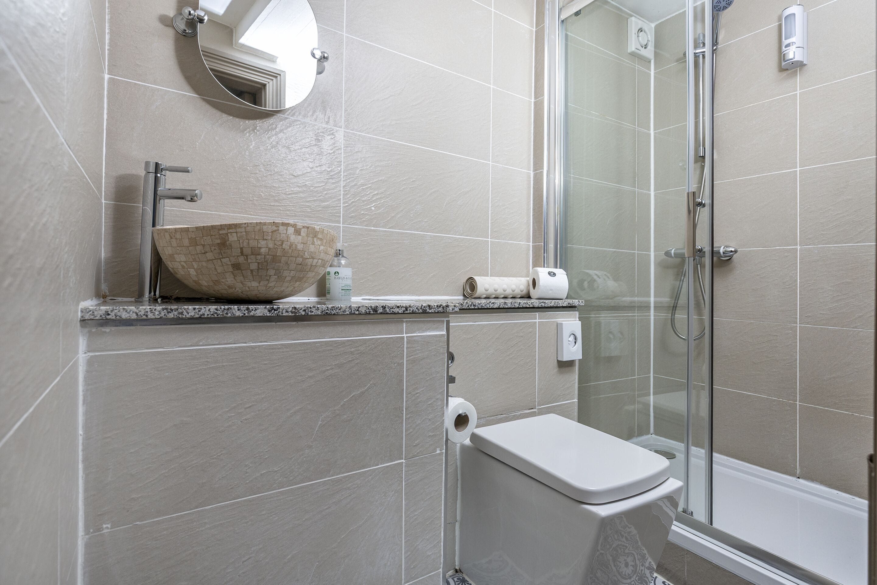 Uma casa de banho moderna com uma lavatório de design, sanita e zona de chuveiro com proteção em vidro.