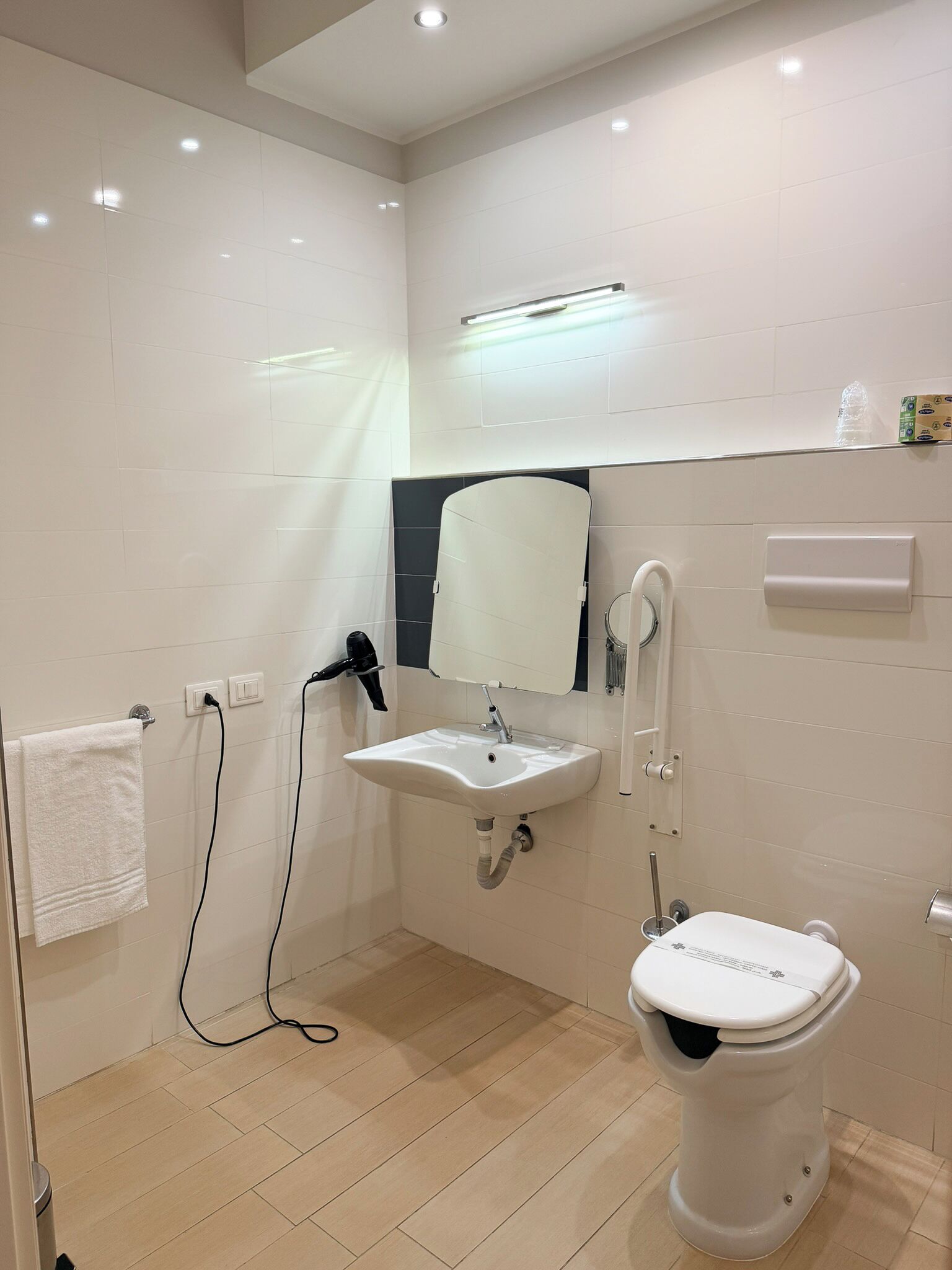 A modern bathroom with a white sink, mirror, and toilet.