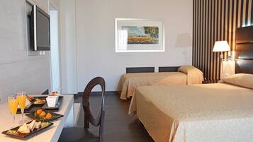 Une chambre d’hôtel avec deux lits, un bureau avec un petit-déjeuner, une télévision et un tableau au mur.