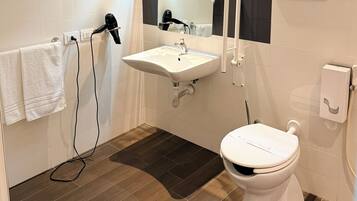 Un bagno con un lavandino bianco, un water e un asciugacapelli fissato a una parete.