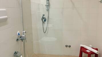 A modern bathroom with a glass shower enclosure, a toilet, and a red stool.