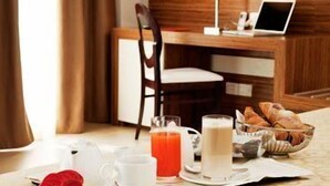 Una mesa de desayuno con un ordenador portátil, una silla y una bandeja de cruasanes, zumo y leche.