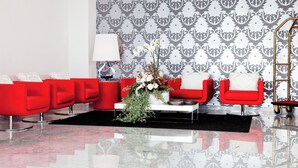 Una sala de estar moderna con sofás rojos, una mesa de centro blanca y un papel tapiz estampado.
