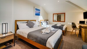 Een hotelkamer met twee bedden, een bureau met een stoel, een flatscreen televisie en een ingelijst schilderij aan de muur.