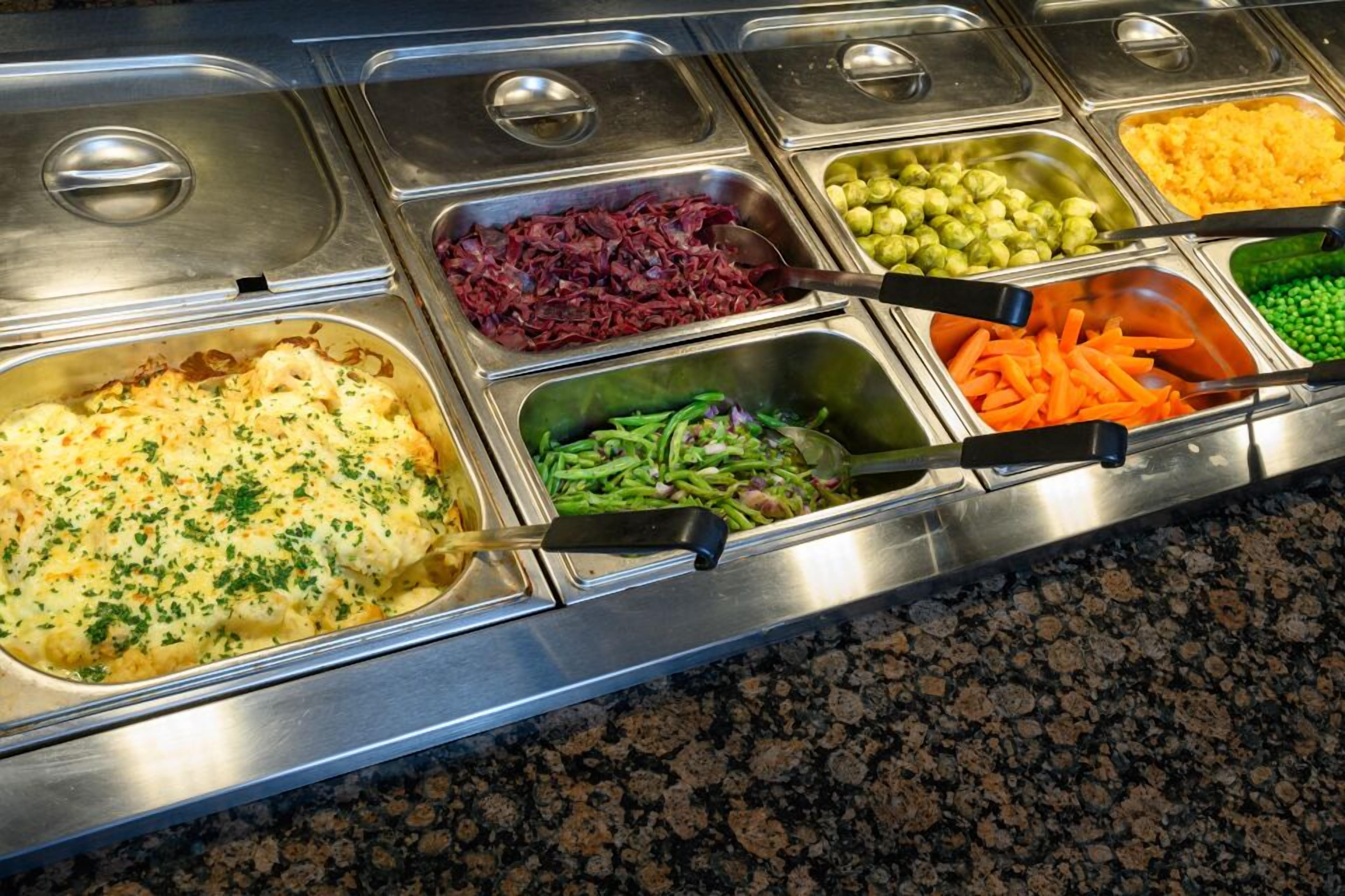 A buffet with various food items including pasta, vegetables, and a casserole.