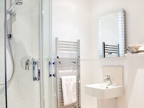 A modern bathroom with a glass shower enclosure, a towel rack, a vanity with a mirror, and a sink. - The Victoria Inn (Truro)