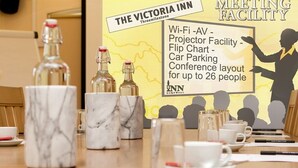 Een congreszaal in Victoria Inn met een houten tafel, bekers met een marmerpatroon en flessen. Faciliteiten omvatten Wi-Fi, een beamer, een flip-over, parkeergelegenheid voor auto's, en een indeling geschikt voor maximaal 26 personen.