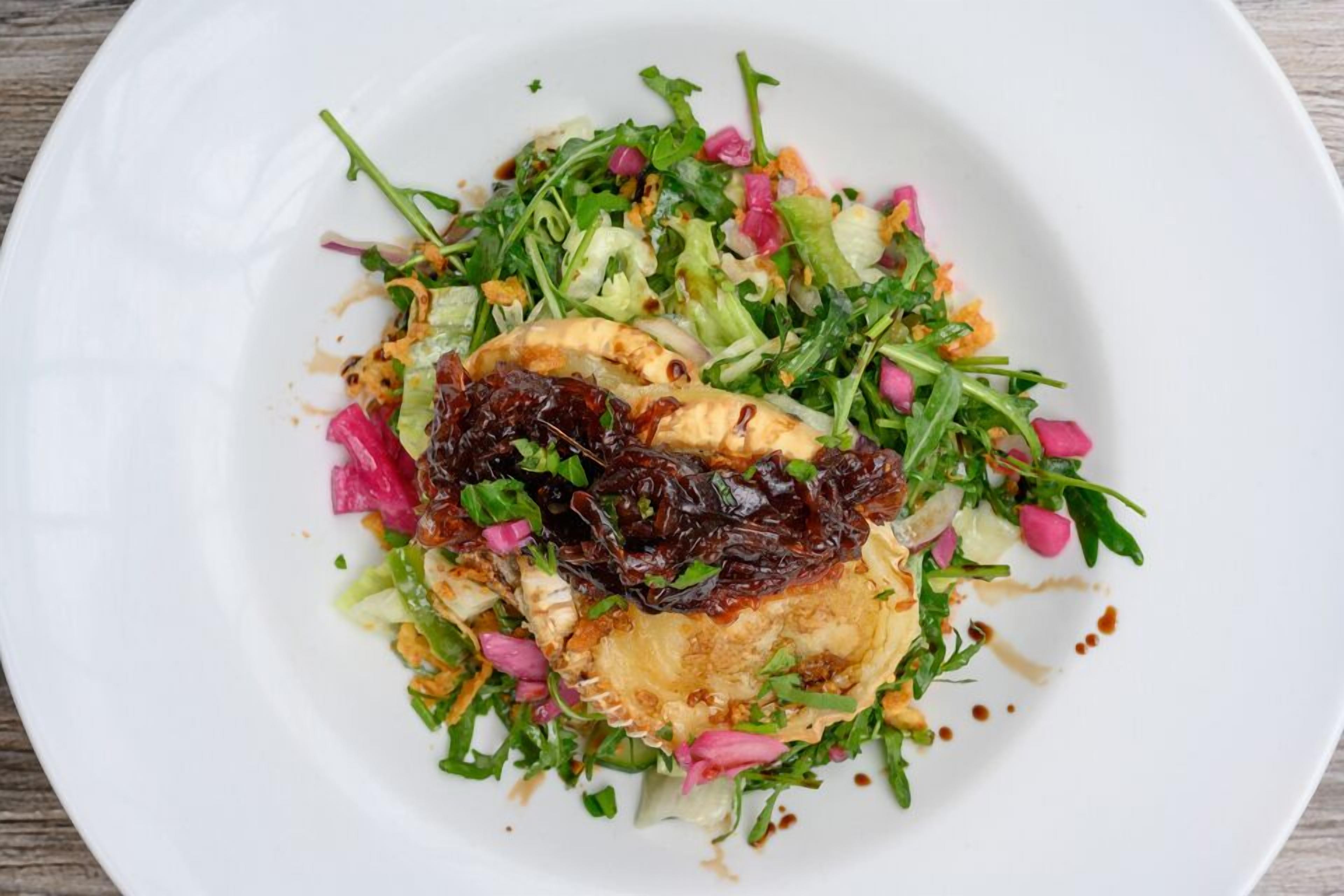 Ein weißer Teller mit Salat und einem gegrillten Hähnchenstück.