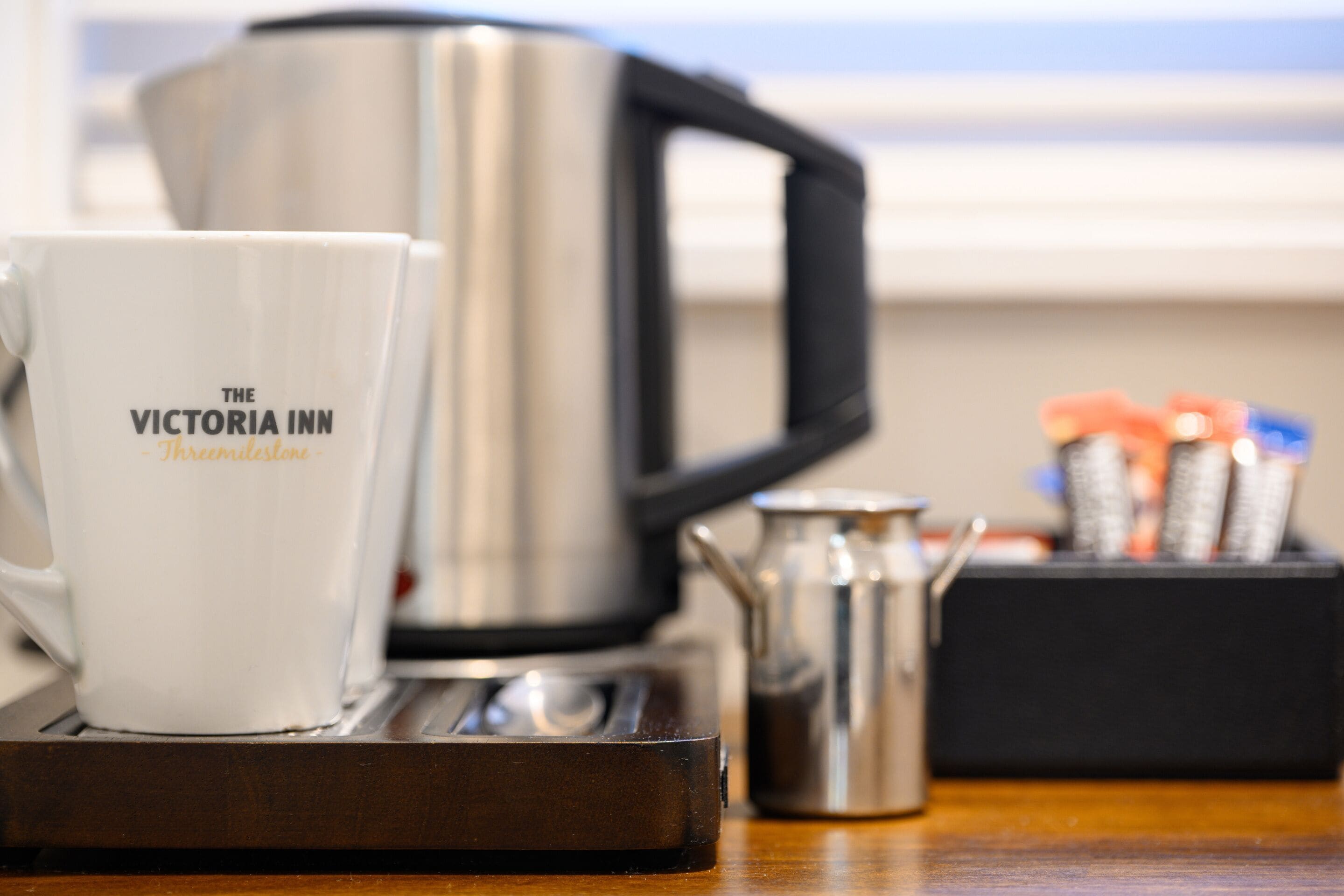 A coffee maker, a white mug with text, and a thermos on a tray.