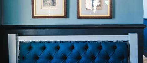 A dining area with a dark wooden table, a blue upholstered bench, and two framed pictures on the wall.