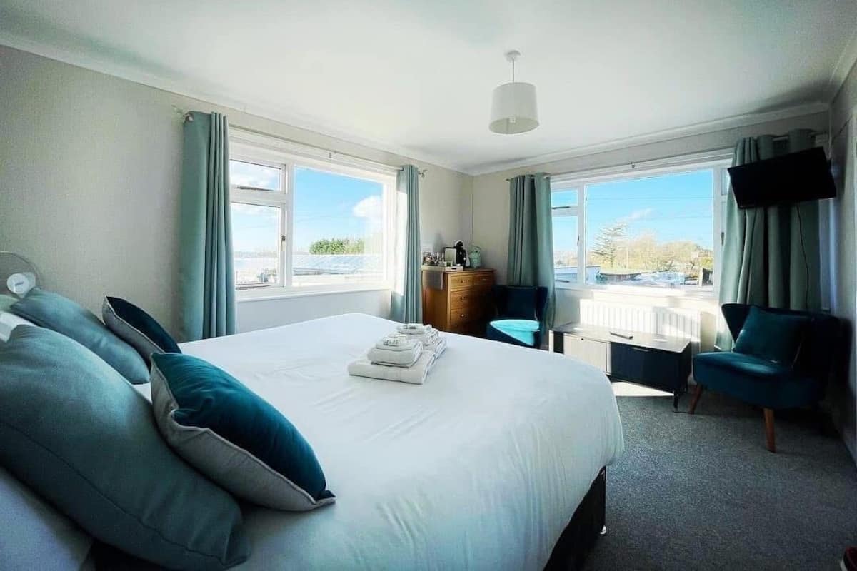 A hotel room with a large bed, a desk, a chair, and a TV.
