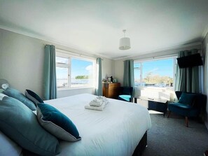 A hotel room with a large bed, a desk, a chair, and a TV. - Sandyhill Guest House (Saundersfoot)