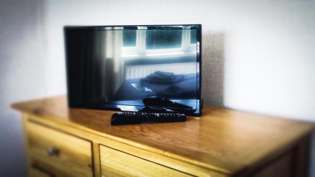 Een televisie op een houten dressoir, met een afstandsbediening ervoor.