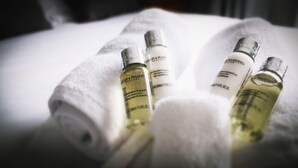 Tre flaconi di prodotti per la cura dei capelli su un asciugamano bianco.